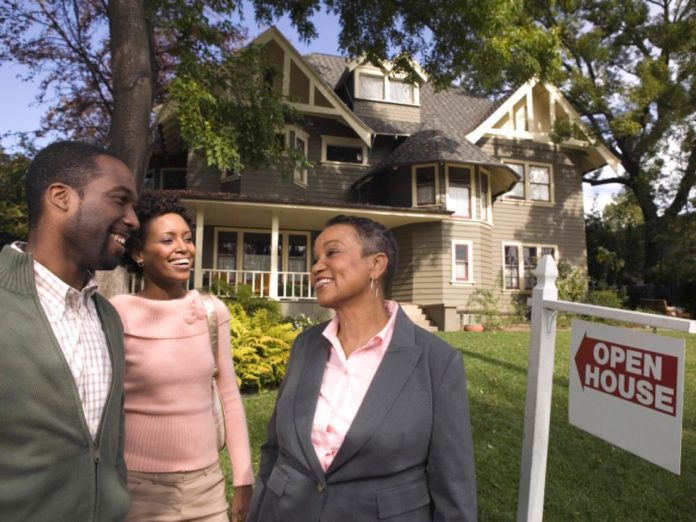 Potential buyers talking with a real estate agent outside an open house. Using seller's assist is a great way to reduce your down payment on a home